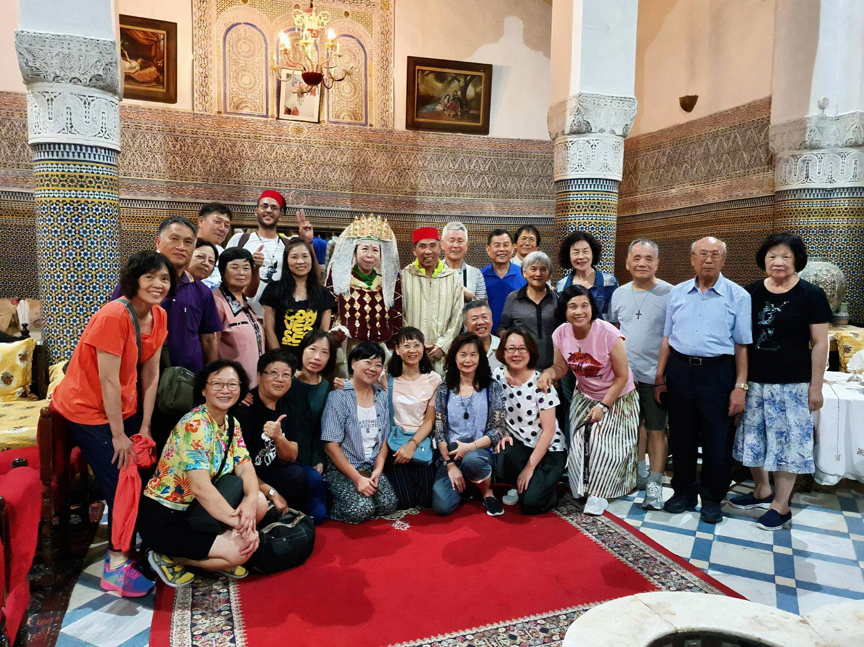 Reda Akrime with 20 Chinese tourists in Moroccan wedding outfits, laughing during a cultural experience in Morocco