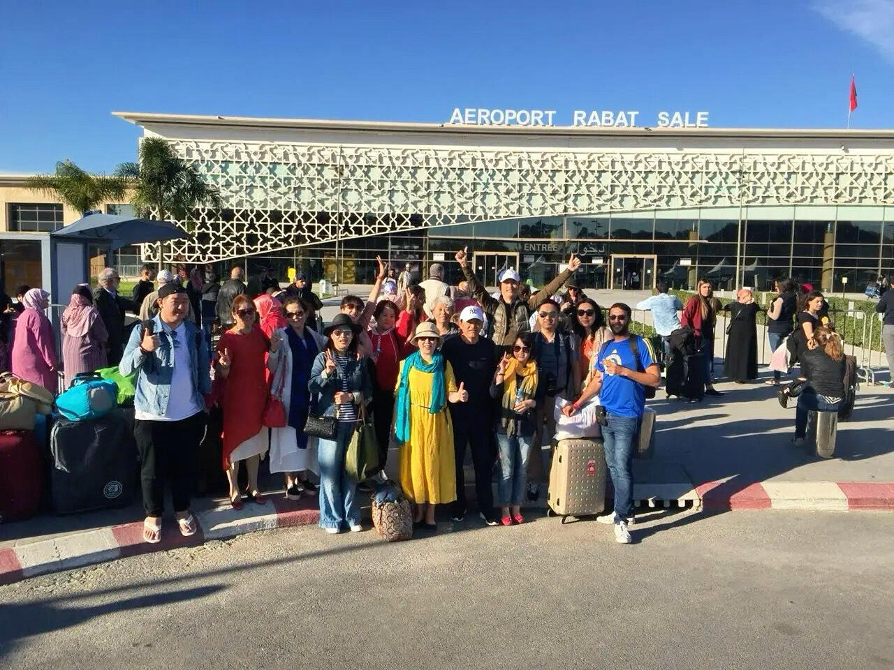 Welcoming Chinese Tour Groups at Rabat Airport Reda Akrime with 10 Chinese tourists and luggage at Rabat airport in Morocco, giving thumbs up in group photo