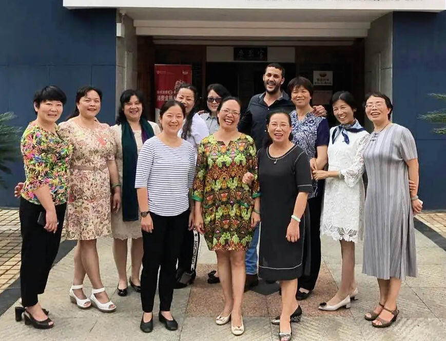 Reda Akrime with 10 Chinese tourists dressed elegantly in front of a Moroccan restaurant, taking a group photo