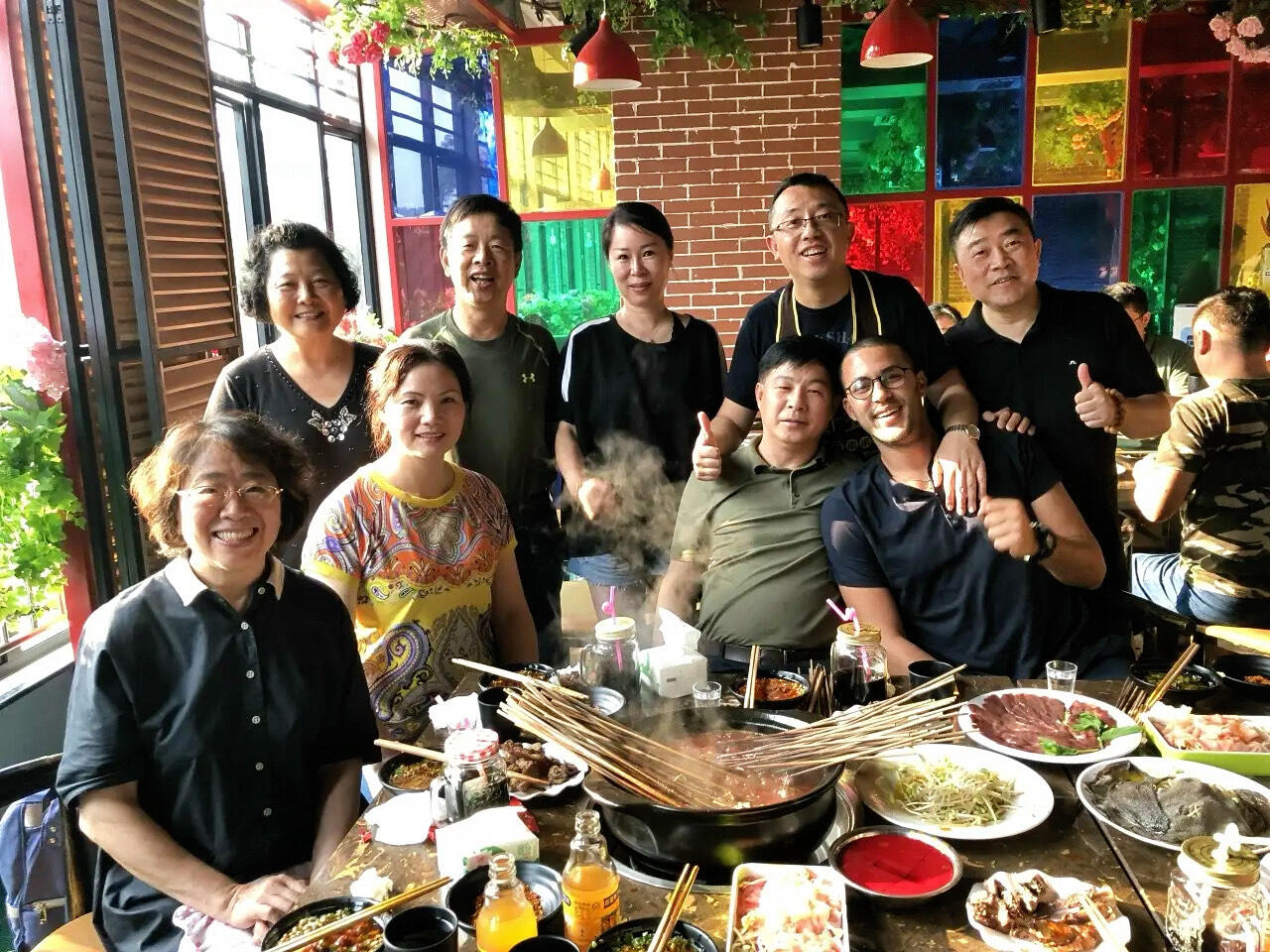 Building Lasting Bonds with Chinese Tour Groups Reda Akrime hugged by Chinese tourist at a restaurant, with group giving thumbs up and smiling in Morocco